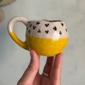 Taza gres amarilla y corazones negros hecha por agalma ceramics