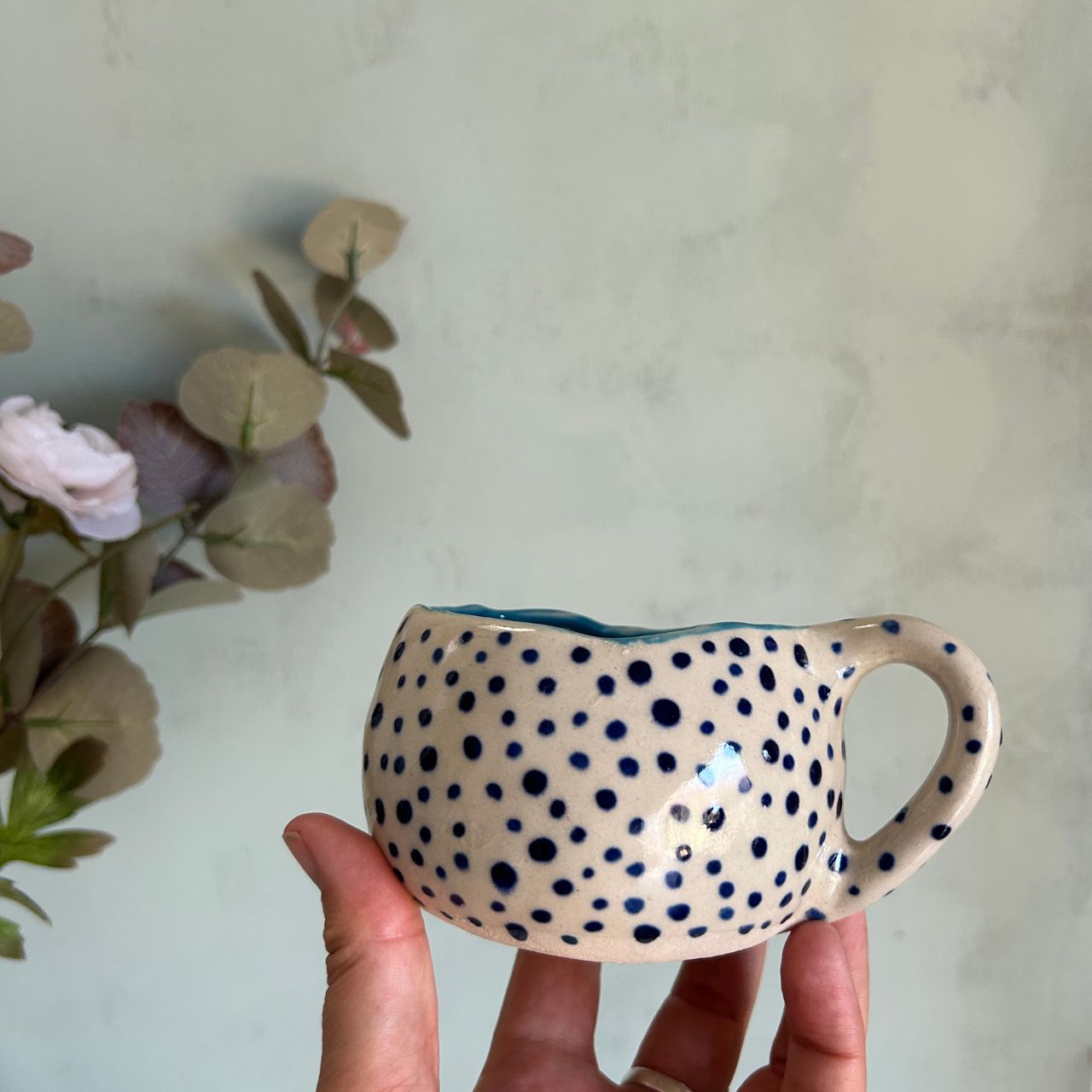 Taza mediana blanca de cerámica con lunares azul oscuro e interior azul claro