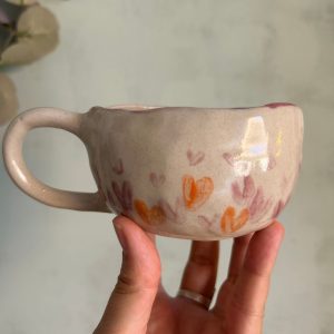 Taza de gres con corazones rosas y naranjas suaves hecha por agalma ceramica