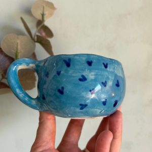Taza mediana azul claro de cerámica artesanal con corazones azul oscuro