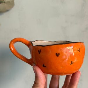 taza naranja con corazones marrones hecha por agalma ceramics